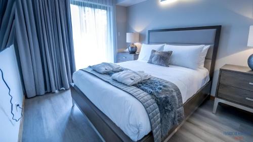 sypialnia z dużym łóżkiem z białą pościelą i poduszkami w obiekcie Château Morritt w mieście Mont-Tremblant