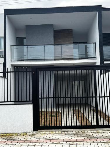 a house with a black gate in front of it at Sobrado Home beach, 4 suites, piscina privativa e conforto expecional in Piçarras