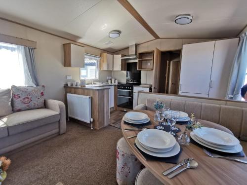 una cocina y una sala de estar con una mesa con platos. en Lovely Caravan With Decking At Solent Breeze In Hampshire Ref 38195sb en Warsash