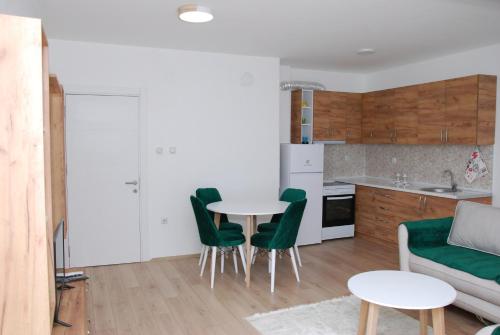 a kitchen with a table and green chairs in a room at Apartman Delevi in Strumica