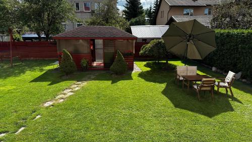 einen Hinterhof mit einem Tisch und einem Regenschirm im Gras in der Unterkunft Japandi apartamentai in Kaunas