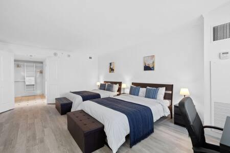 two beds in a white room with two chairs at 2BR 3BA Ocean Front condo on the Boardwalk CozySuites in Atlantic City