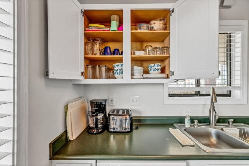 a kitchen with white cabinets and a sink and a counter at Seas The Day with Fantastic Marina Views in Carolina Beach