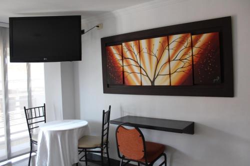 comedor con mesa y TV en la pared en Hotel Andinos Plaza Pitalito, en Pitalito