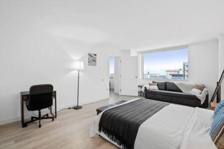 Un dormitorio con una cama, un escritorio y un sofá. en Huge 2BR 3BA Ocean Front Condo by CozySuites, en Atlantic City