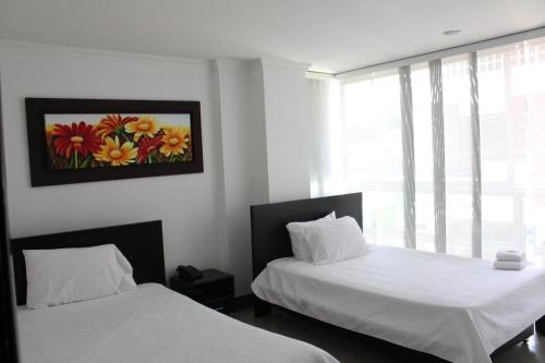 a bedroom with two beds and a painting on the wall at Hotel Andinos Plaza Pitalito in Pitalito