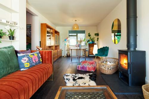 a living room with a red couch and a wood stove at Kent Downs Cottage Modern Family Retreat near Canterbury in Canterbury