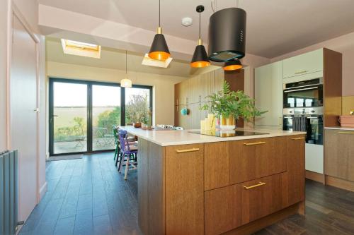 a kitchen with wooden cabinets and a large island at Kent Downs Cottage Modern Family Retreat near Canterbury in Canterbury