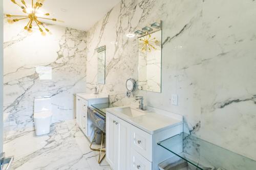 a bathroom with two sinks and a marble wall at Modern Catskill House & Lake NY with hot tube on the roof in Stamford