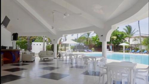 uma piscina com mesas e cadeiras brancas e uma piscina em DIVERSITY HOTEL em Sosúa