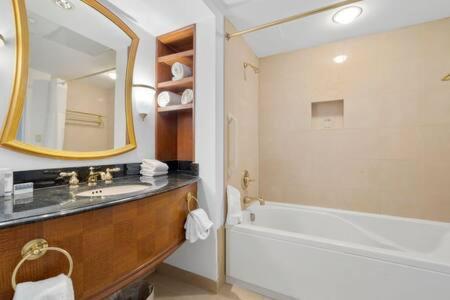 a bathroom with a sink and a tub and a mirror at CozySuites at Showboat Bold 2BR 3BA Beachfront in Atlantic City
