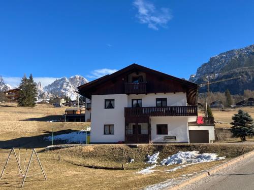 una casa en un campo con montañas en el fondo en Affittacamere Iragidor, en Cortina dʼAmpezzo