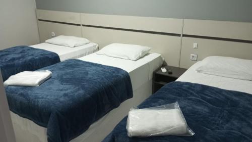 a room with two beds with blue and white sheets at HOTEL BARLOS ADUANA in Uruguaiana