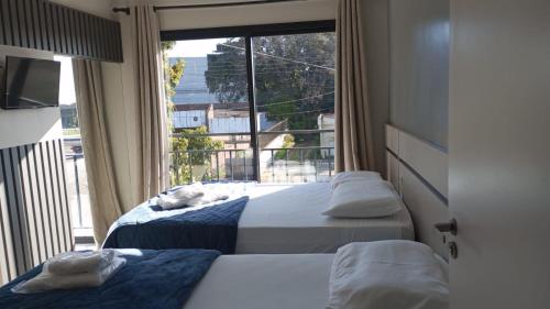 um quarto com 2 camas e uma grande janela em HOTEL BARLOS ADUANA em Uruguaiana