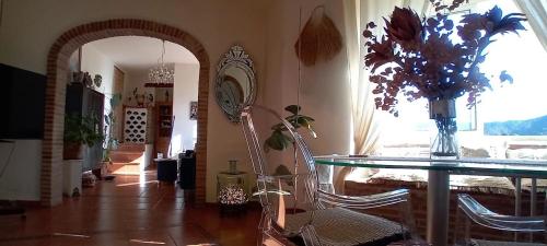 un comedor con una mesa de cristal y un jarrón de flores en Posada Puente Romano, en Sedella