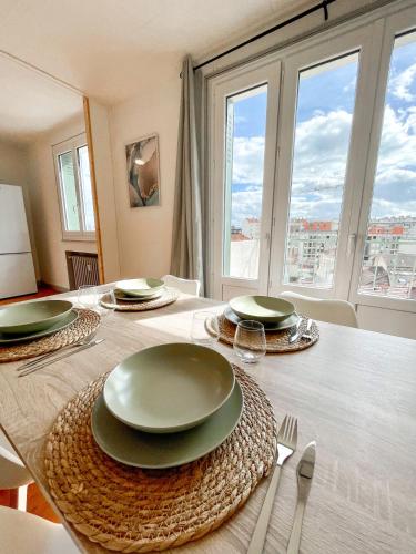 - une salle à manger avec une table et des assiettes dans l'établissement Le Bel Horizon - Chaleureux & Lumineux proche gare, à Roanne