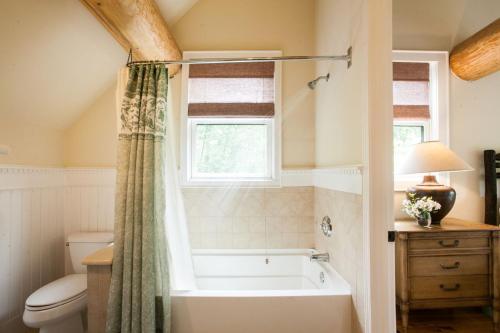 La salle de bains est pourvue d'une baignoire, de toilettes et d'une fenêtre. dans l'établissement Black Mountain Log Cabin Secluded, Pet-friendly 3BD with Hot Tub & Views!, à Black Mountain
