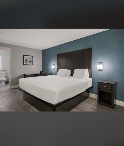 um quarto com uma grande cama branca e uma parede azul em Rodeway Inn San Antonio Downtown em San Antonio