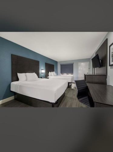 1 dormitorio con 1 cama blanca grande y paredes azules en Rodeway Inn San Antonio Downtown en San Antonio