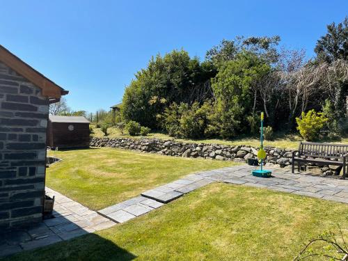 a garden with a bench and a stone wall at Yr Encil in Gaerwen
