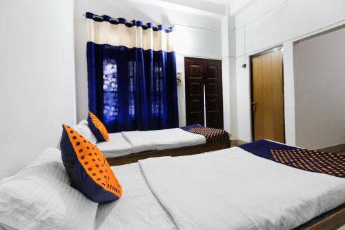 two beds in a room with blue curtains at SPOT ON 60631 Janta Guest House in Dispur