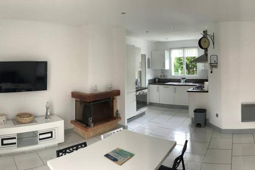 Il comprend une cuisine blanche avec une table et une télévision. dans l'établissement Maison « Au petit Bonheur » chatelaillon plage, à Châtelaillon-Plage