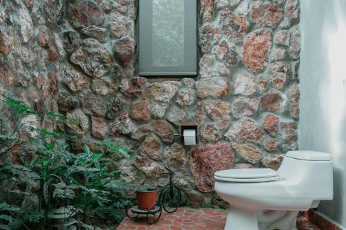 a stone bathroom with a toilet and a stone wall at La Perezosa in Cerro Azul