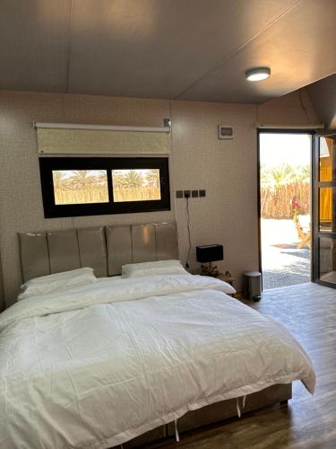 Schlafzimmer mit einem großen weißen Bett und einem Fenster in der Unterkunft كوخ الملاذ الريفي MalathCottage in Al-'Ula