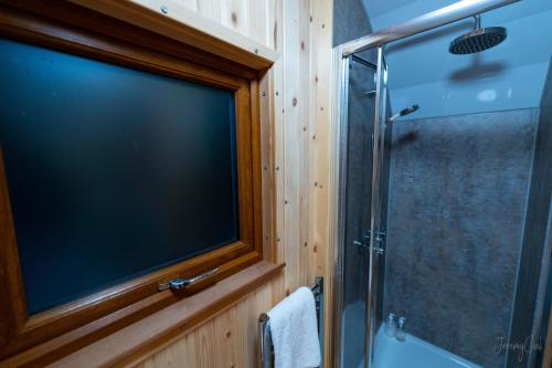 TV grande en el baño con ducha en Missin' Link Glamping en West Hoathley