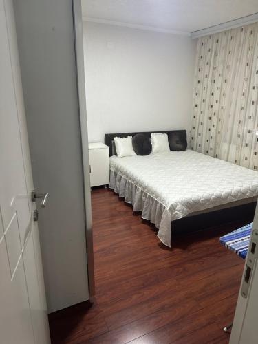 zvezda marjan في كوكاني: غرفة نوم بسرير ذو شراشف بيضاء وارضيات خشبية