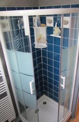 La salle de bains est pourvue d'une douche et de murs carrelés bleus. dans l'établissement L'Abri Côtier, à Yport