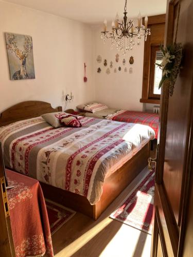 a bedroom with two beds and a chandelier at Ciasa Nonna Bon Bon in Cortina dʼAmpezzo