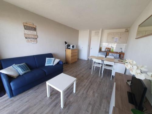 un salon avec un canapé bleu et une cuisine dans l'établissement Studio dans une résidence - S04107, à Soulac-sur-Mer