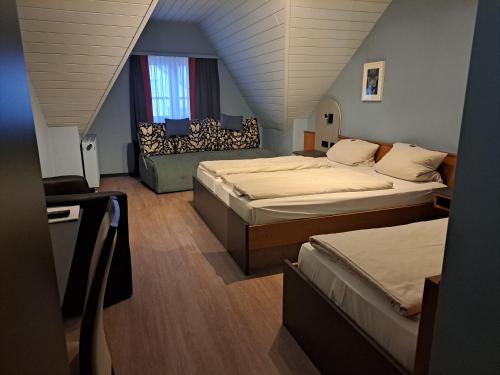 een slaapkamer op zolder met 2 bedden en een bank bij Gasthaus Sonne GbR in Trennfeld