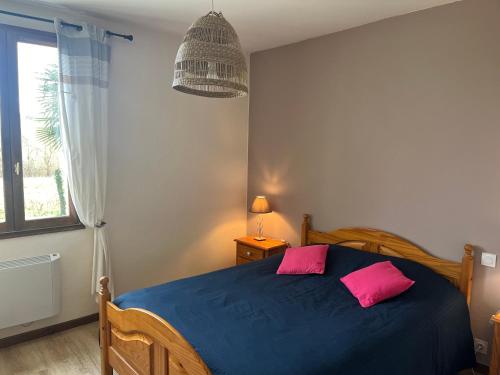 ein Schlafzimmer mit einem blauen Bett mit zwei rosa Kissen in der Unterkunft Petite maison indépendante in Nay