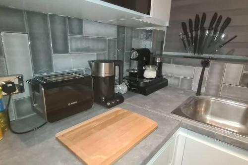 a kitchen with a counter top with a coffee maker and a cutting board at Top Hat Luton flat free parking in Luton