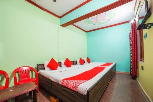 a bedroom with a bed and a red chair at OYO 66014 The Rudralok Hotel in Gopeshwar