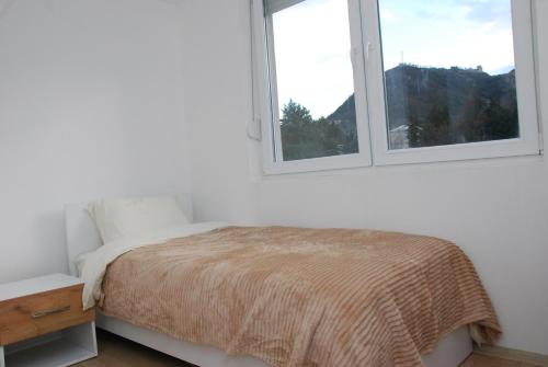 a white bedroom with a bed and two windows at Apartman Delevi in Strumica