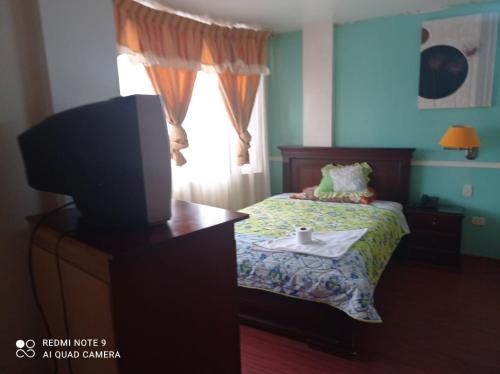 1 dormitorio con 1 cama, TV y ventana en Hotel RITZOR, en Latacunga
