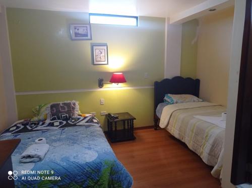 Dormitorio pequeño con 2 camas y lámpara en Hotel RITZOR, en Latacunga