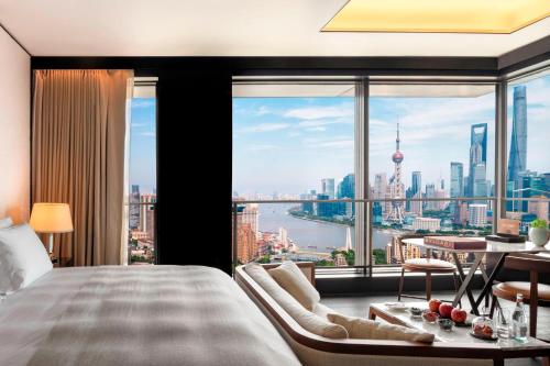 上海市にあるブルガリ ホテル 上海のベッドルーム1室(市街の景色を望む大きな窓付)