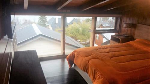 ein Schlafzimmer mit einem Bett und einem großen Fenster in der Unterkunft Las Agustinas DAT in San Carlos de Bariloche