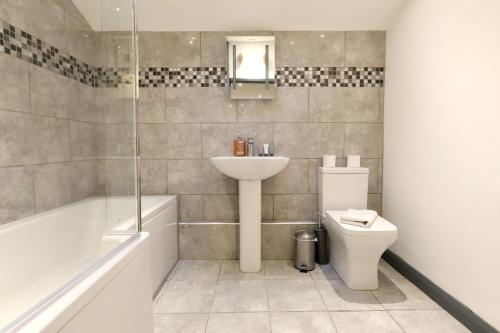 a bathroom with a sink and a toilet and a bath tub at The Old Corn Store Rural Escape Farmstay Barn in Norwich