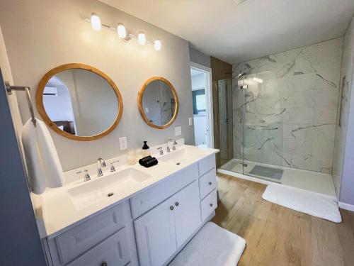 een badkamer met 2 wastafels en een douche bij Finn's Hideaway -Modern family river home in Keokuk
