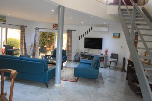 a living room with blue couches and a tv at Amour Sénégal in Ngaparou