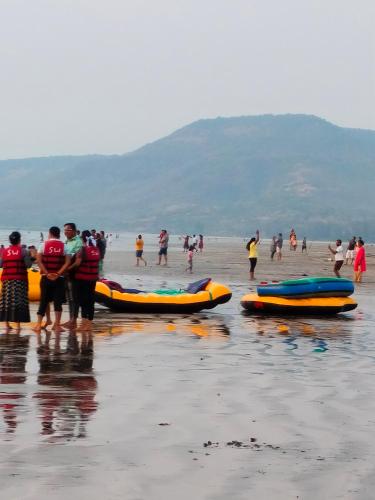 a group of people standing on a beach with canoes at Om Laxmi Narayan Homestay in Diveagar