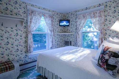 a bedroom with a bed and two windows at Heart of the Village Bed & Breakfast in Shelburne VT in Shelburne