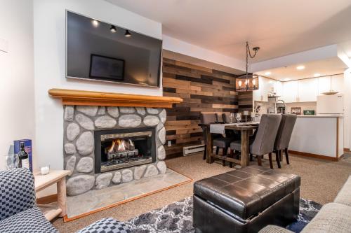 uma sala de estar com lareira e uma televisão por cima em Creekside Slopeside 1BR with pool, hot tub, BBQ em Whistler