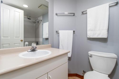 a white bathroom with a sink and a toilet at Creekside Slopeside 1BR with pool, hot tub, BBQ in Whistler