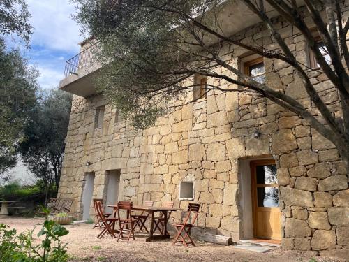 une table et des chaises devant un bâtiment en pierre dans l'établissement Villa proche plage extrême sud Corse, à Monacia-dʼAullène